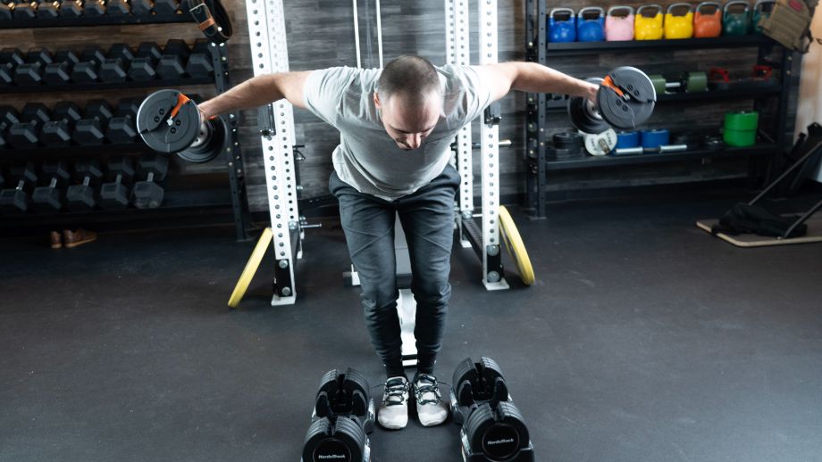 Man performing bent flyes with the Nordictrack dumbbells